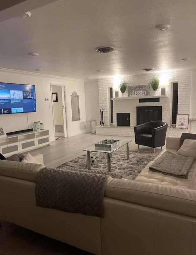 living room with hardwood / wood-style flooring, crown molding, and a fireplace