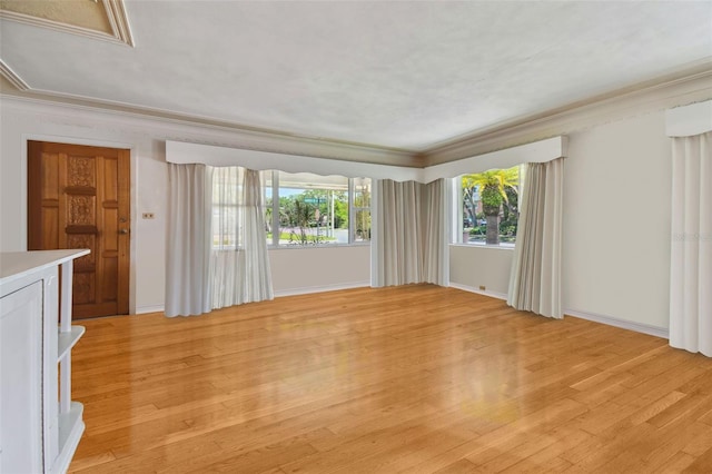 unfurnished living room with ornamental molding and light hardwood / wood-style floors