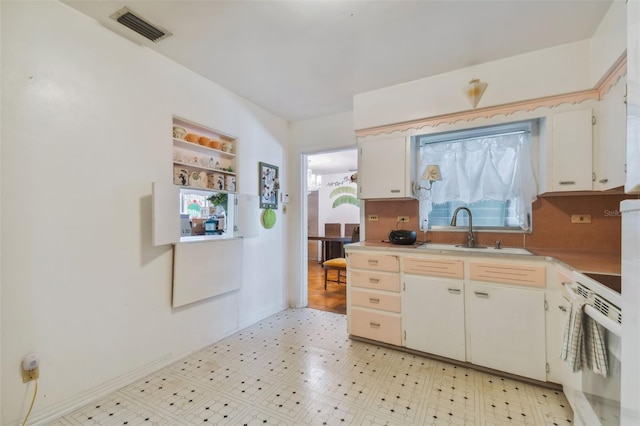 kitchen with tasteful backsplash, white cabinetry, sink, and white range with electric cooktop