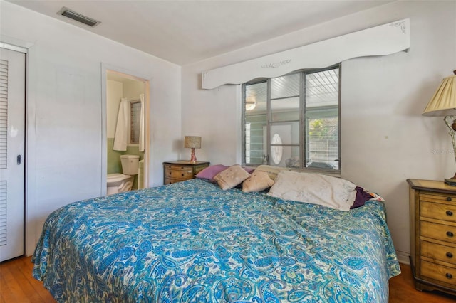 bedroom with hardwood / wood-style floors and ensuite bath