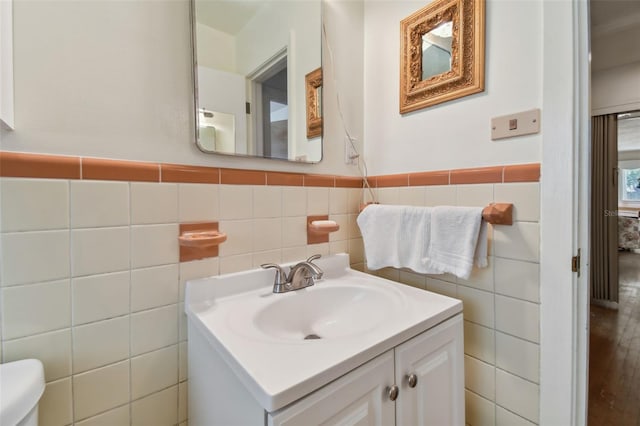 bathroom featuring vanity, tile walls, and toilet