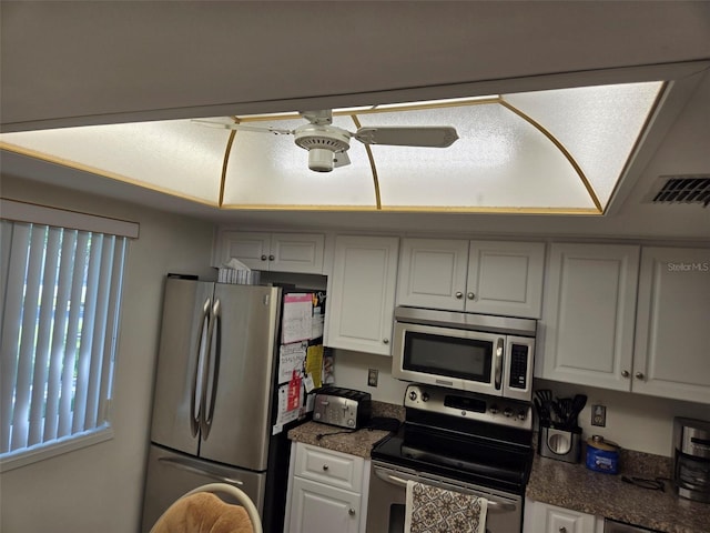 kitchen with appliances with stainless steel finishes, white cabinets, and ceiling fan