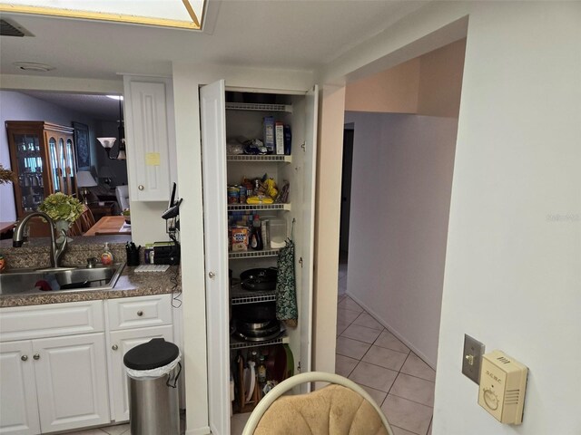 kitchen with white cabinets, sink, and light tile patterned floors