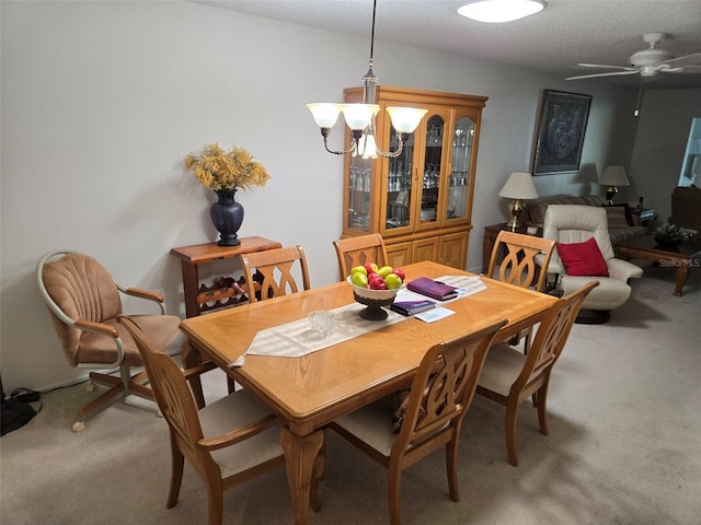 dining room with light colored carpet, a textured ceiling, and ceiling fan with notable chandelier