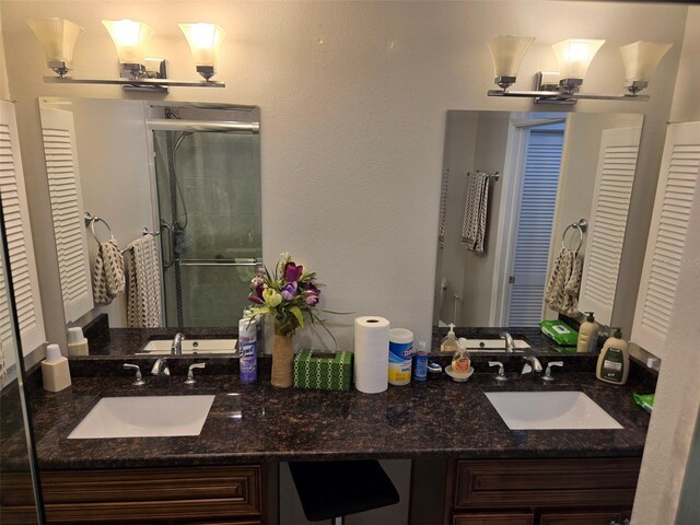 bathroom with a shower with door and double sink vanity