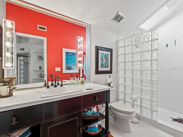 bathroom with vanity, tiled shower, tile patterned floors, a skylight, and toilet