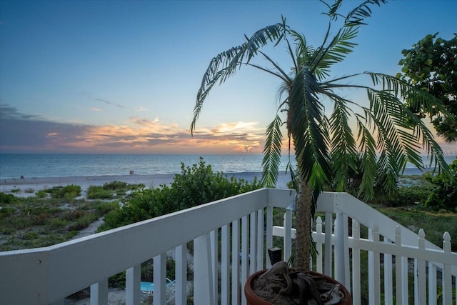 balcony at dusk featuring a water view