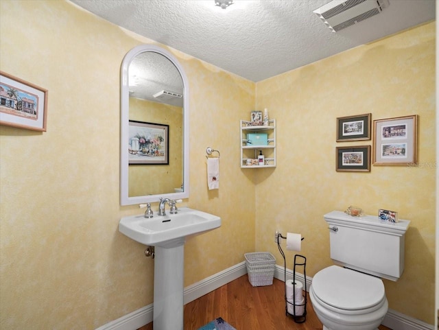 bathroom with sink, a textured ceiling, wood-type flooring, and toilet