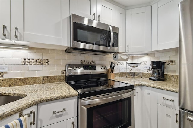 kitchen with decorative backsplash, appliances with stainless steel finishes, light stone countertops, and white cabinets