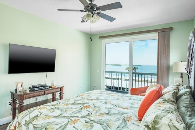 bedroom with access to exterior, ceiling fan, and a water view