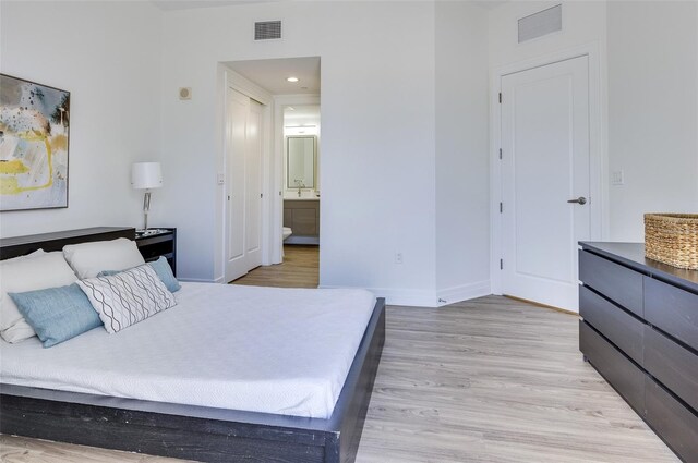 bedroom with ensuite bathroom and light hardwood / wood-style floors