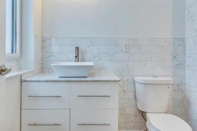 bathroom with tile walls, toilet, and vanity