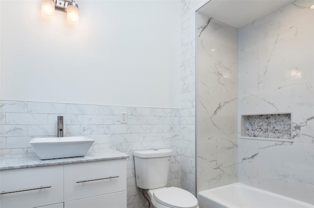 full bathroom featuring vanity, tasteful backsplash, tile walls, tiled shower / bath combo, and toilet