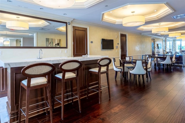 bar with dark hardwood / wood-style flooring, pendant lighting, a raised ceiling, and crown molding