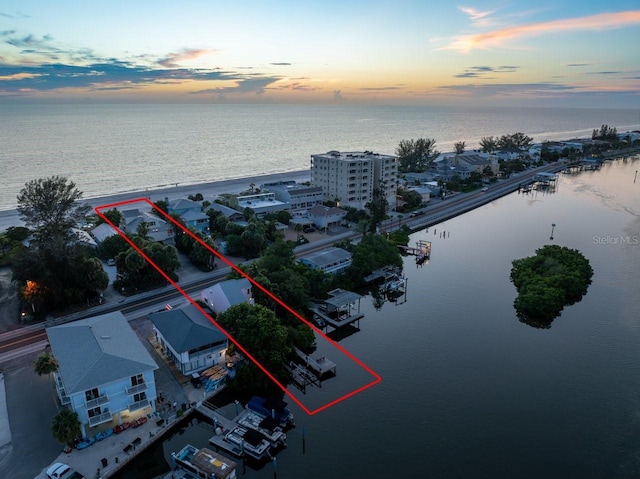 aerial view at dusk featuring a water view