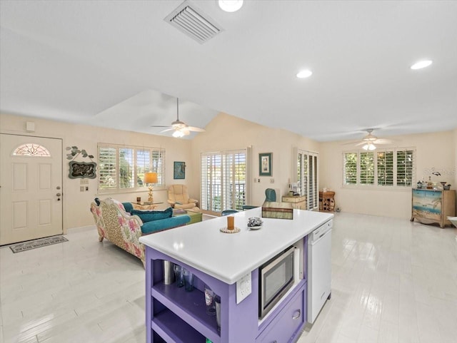 kitchen featuring stainless steel microwave, dishwasher, ceiling fan, and a center island