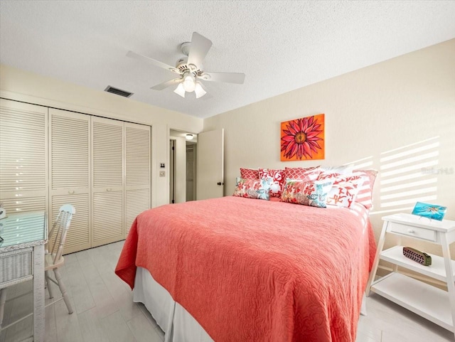 bedroom featuring a textured ceiling, a closet, light wood-type flooring, and ceiling fan