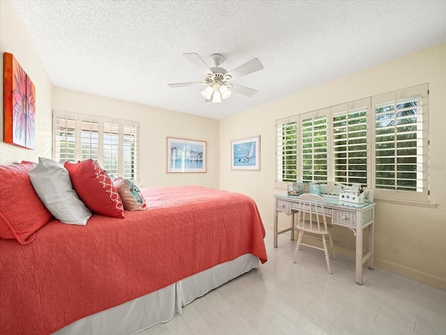 bedroom with multiple windows, a textured ceiling, ceiling fan, and light hardwood / wood-style flooring