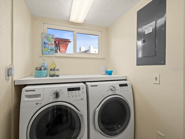 clothes washing area with a textured ceiling, separate washer and dryer, and electric panel