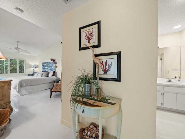 hall with sink, a textured ceiling, and light tile patterned floors