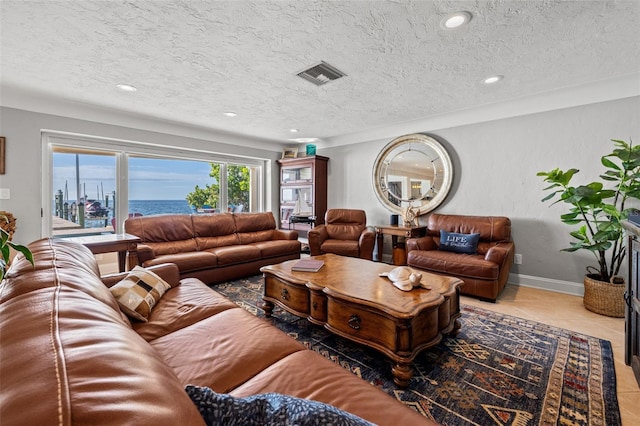 tiled living room with a textured ceiling and a water view