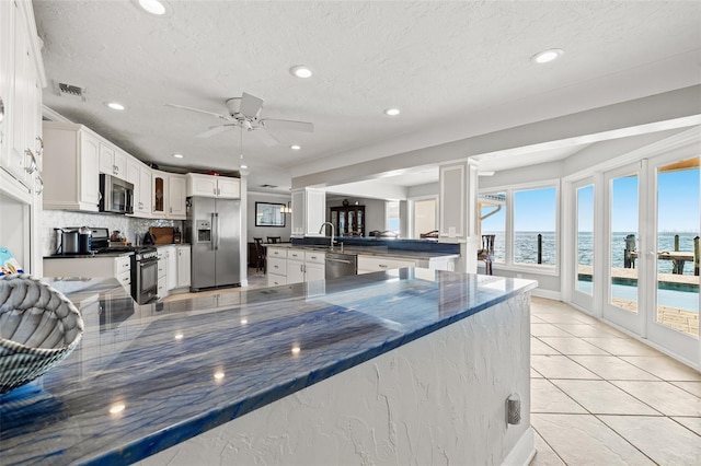 kitchen with sink, stainless steel appliances, a water view, white cabinets, and kitchen peninsula