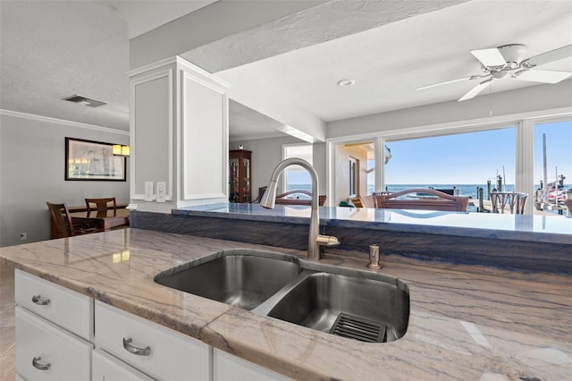 kitchen featuring sink, ceiling fan, light stone countertops, ornamental molding, and white cabinets