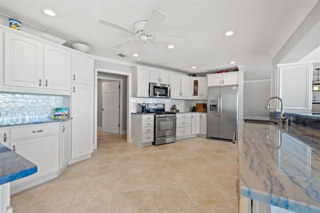 kitchen with sink, tasteful backsplash, light tile patterned floors, stainless steel appliances, and white cabinets