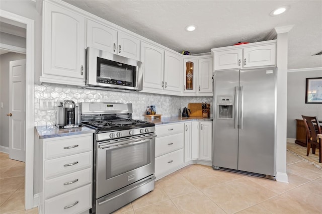 kitchen with light tile patterned flooring, white cabinets, backsplash, stainless steel appliances, and a textured ceiling