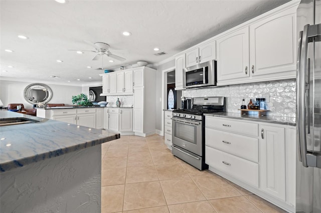 kitchen with sink, white cabinetry, light tile patterned floors, kitchen peninsula, and stainless steel appliances