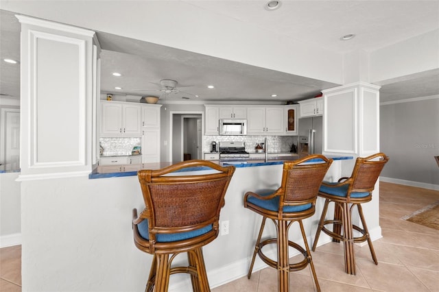 kitchen with white cabinetry, appliances with stainless steel finishes, light tile patterned floors, and kitchen peninsula