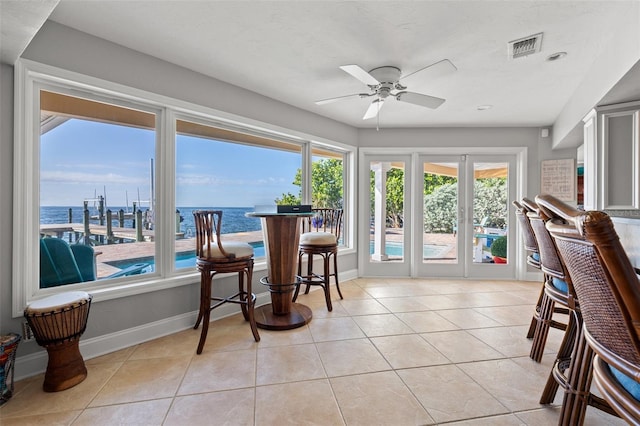 sunroom featuring ceiling fan and a water view