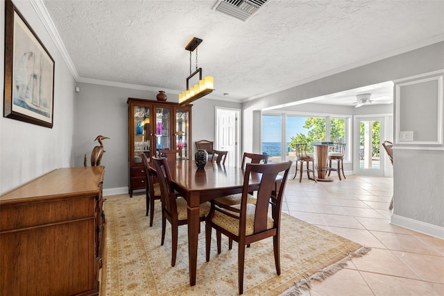 tiled dining space featuring ceiling fan, ornamental molding, and a textured ceiling