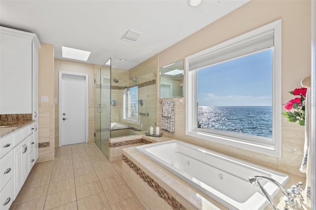 bathroom with tile walls, a skylight, a water view, vanity, and independent shower and bath