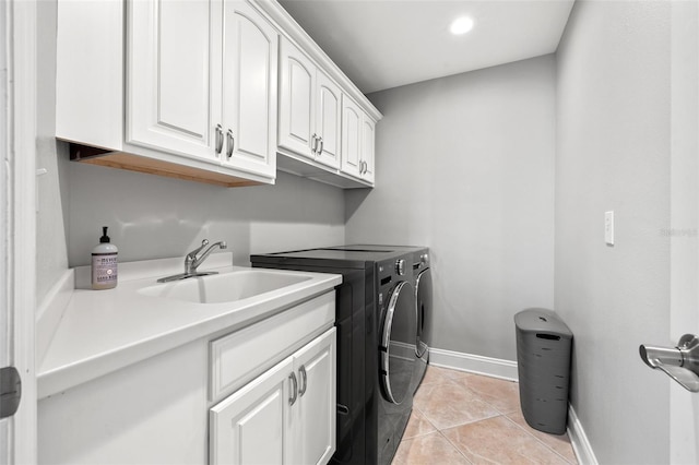 laundry room featuring sink, light tile patterned floors, cabinets, and independent washer and dryer