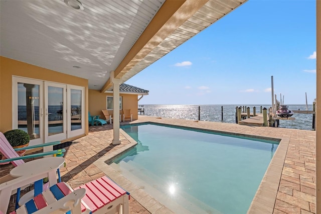 view of pool with a water view, a patio area, and a boat dock