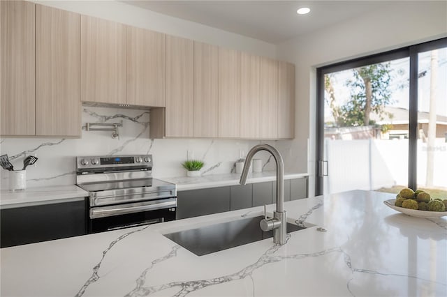 kitchen with electric stove, sink, light stone countertops, decorative backsplash, and light brown cabinets