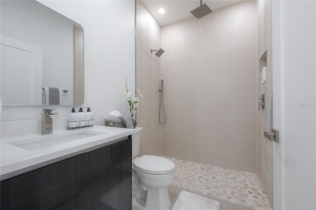 bathroom with vanity, toilet, and a tile shower