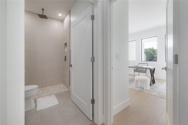 bathroom featuring tiled shower, tile patterned floors, and toilet