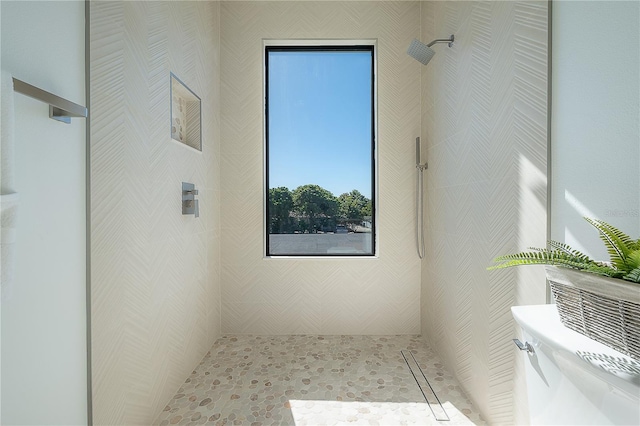 bathroom with a tile shower and toilet