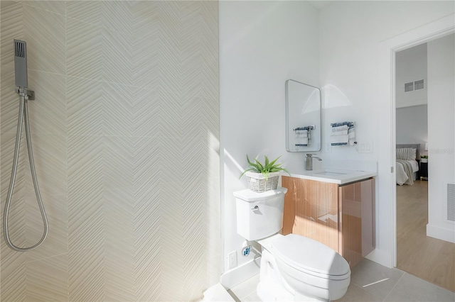 bathroom featuring vanity, tile patterned floors, toilet, and a tile shower