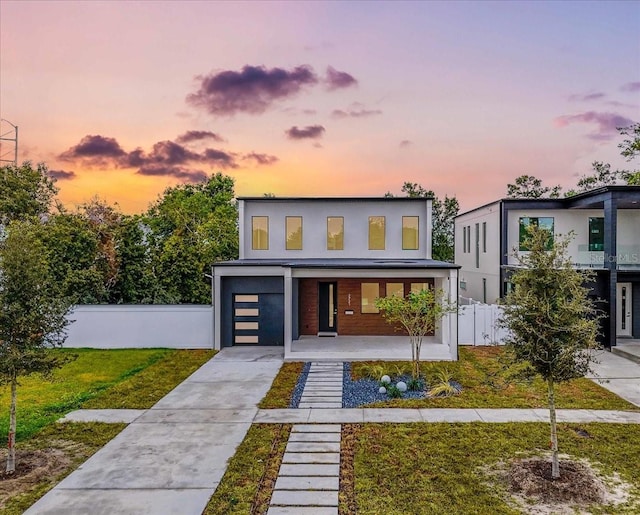 contemporary house with a porch, a garage, and a yard