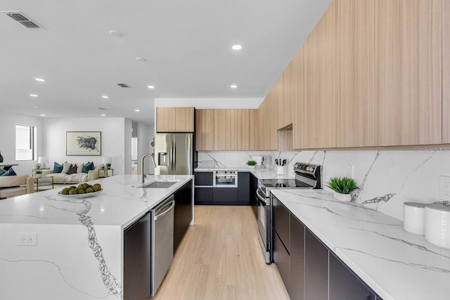 kitchen featuring light wood finished floors, a sink, modern cabinets, visible vents, and appliances with stainless steel finishes