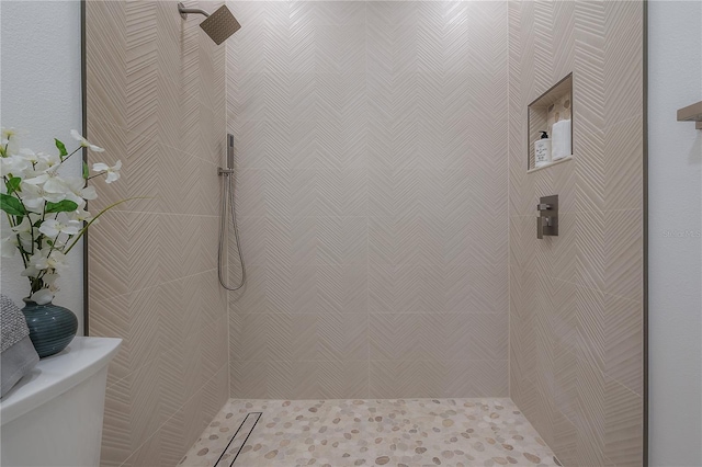 bathroom featuring tiled shower and toilet
