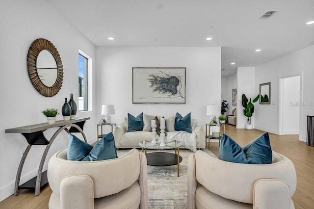 living room featuring baseboards, visible vents, light wood finished floors, and recessed lighting