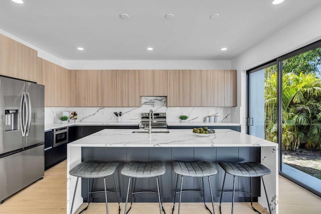 kitchen with stainless steel appliances, a kitchen breakfast bar, modern cabinets, and light wood-style flooring