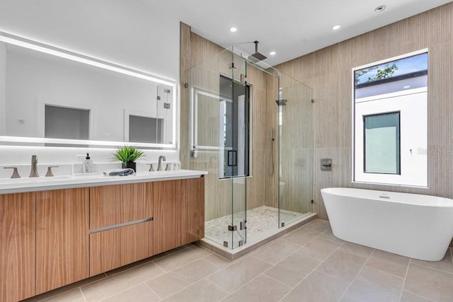 full bath with a soaking tub, a sink, double vanity, a stall shower, and recessed lighting