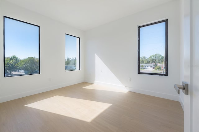 spare room with baseboards and light wood-style floors