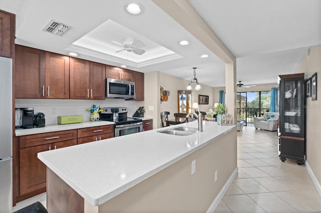 kitchen featuring ceiling fan, sink, stainless steel appliances, and a tray ceiling