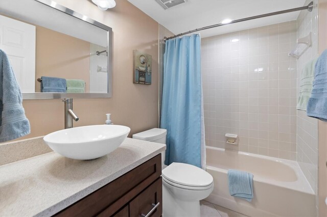 full bathroom featuring tile patterned flooring, toilet, shower / bath combo with shower curtain, and vanity